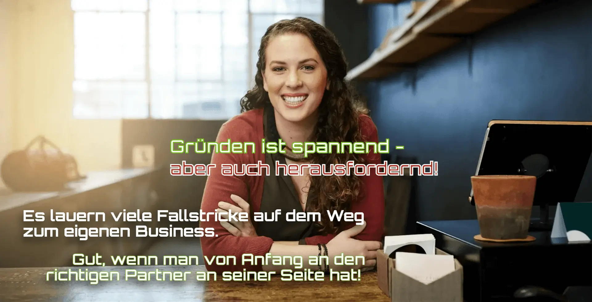 Eine Frau sitzt lächelnd an einem Schreibtisch und arbeitet an ihrem Laptop.