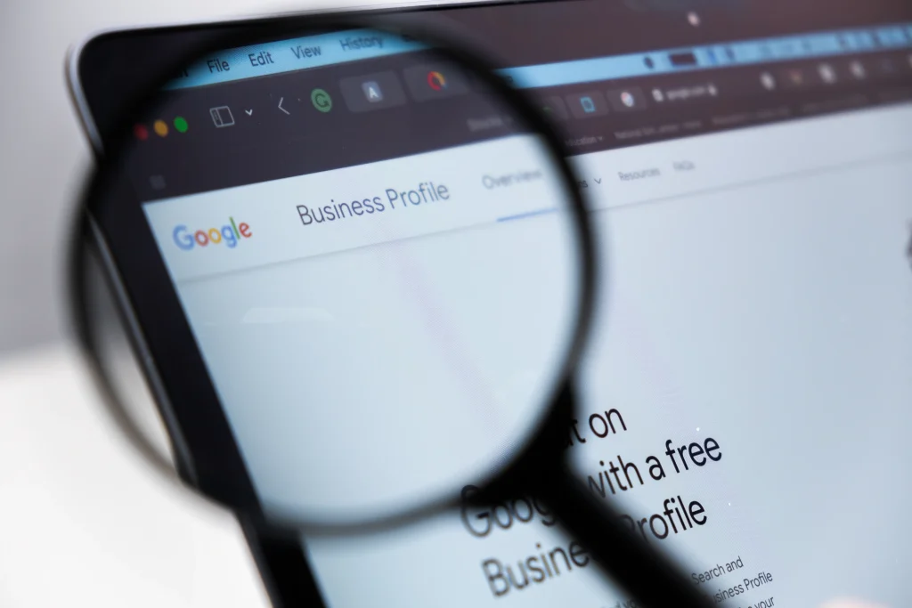 Nahaufnahme eines Computerbildschirms, auf dem die Google Business Profile-Webseite angezeigt wird, wobei eine Lupe auf den Titel „Business Profile“ fokussiert ist.