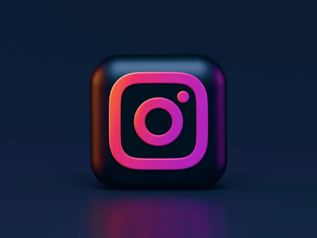 3D-Instagram-Logo mit einem rosa und violetten Farbverlauf auf quadratischem schwarzen Hintergrund vor einem dunkelblauen Hintergrund.