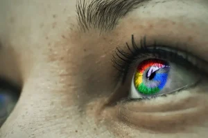 Nahaufnahme des Auges einer Person mit dem in der Pupille reflektierten Google-Logo. Das Auge ist weit geöffnet und die Wimpern und die Haut sind deutlich sichtbar.