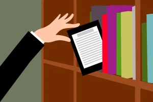 Eine Hand hält einen E-Reader neben einem Bücherregal voller bunter Bücher.